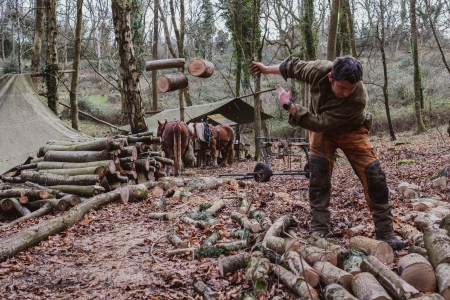A man tossing wood to the side at a campground.