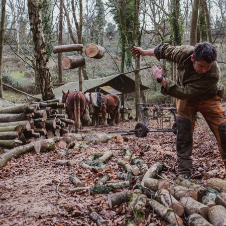 A man tossing wood to the side at a campground.