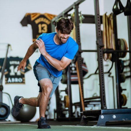 A man lunging across a gym floor.