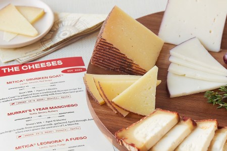 A platter of different cheeses sitting next to a piece of paper describing them