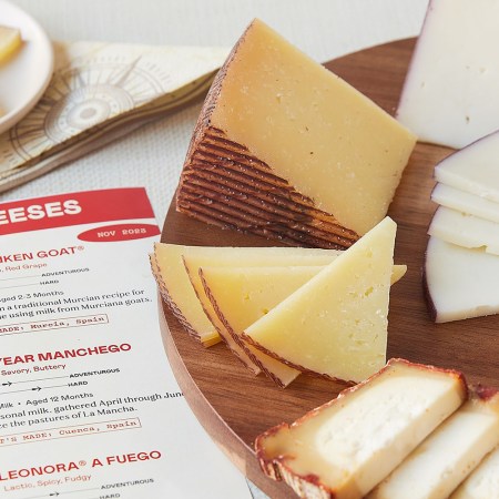 A platter of different cheeses sitting next to a piece of paper describing them