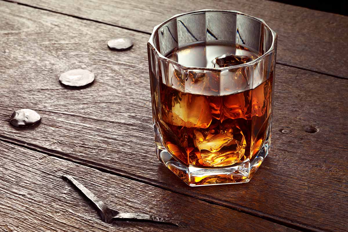 Whiskey with ice in crystal glass on wood table. Many rye whiskies take on a regional characteristic.