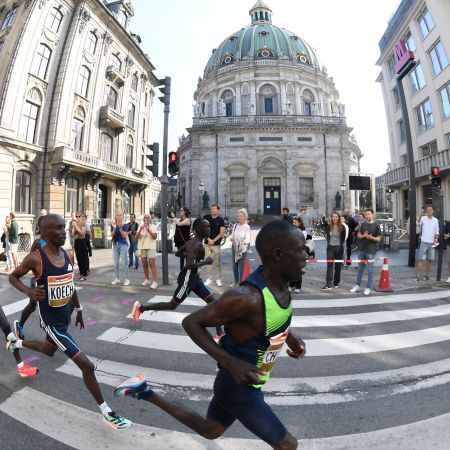 A crew of runners racing past a church in Copenhagen.
