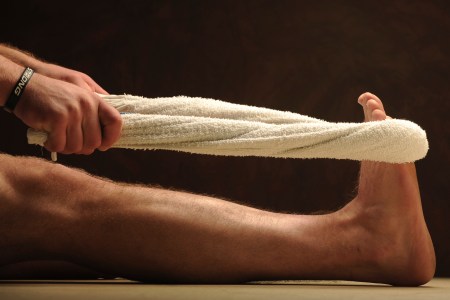 A person stretching their legs with a towel. Working out with a towel is surprisingly effective.