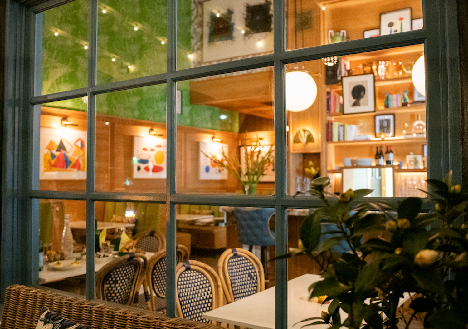 Shot of Bar Cecil from a window showing dining room setting with colorful booth seats and tables