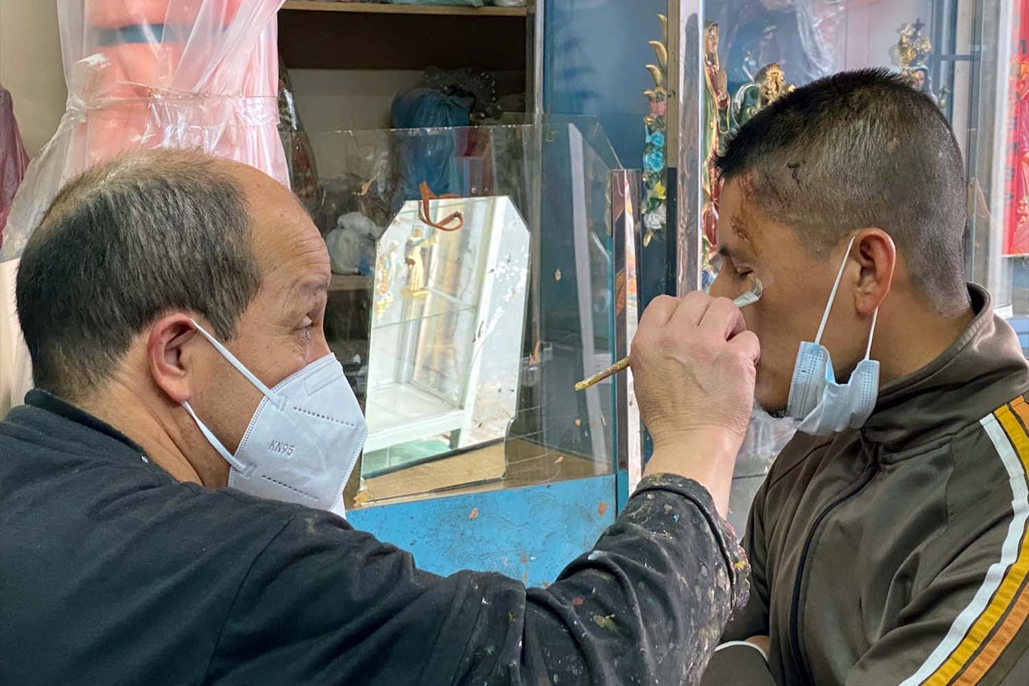 Carrion paints on the face of a young man with fresh cuts and abrasions