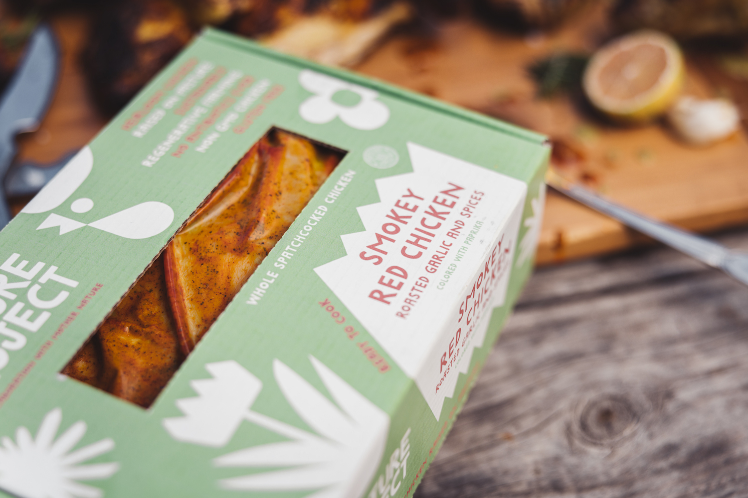 Green and white box holding cooked anf flavored smokey red chicken