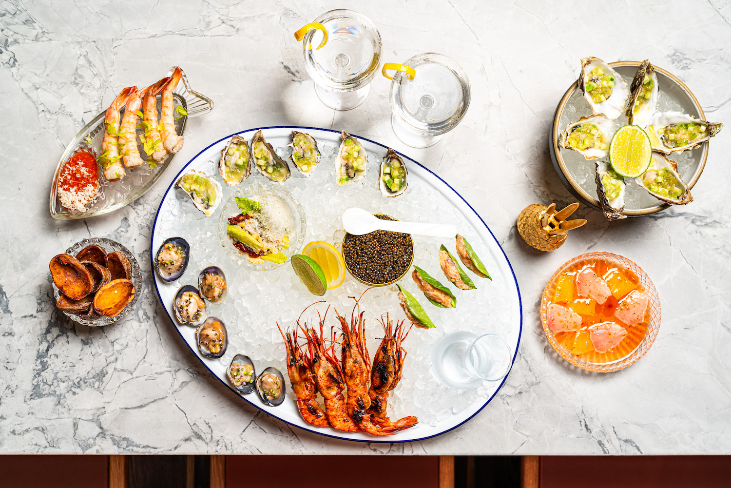 Raw bar with a range of fish on ice, such as shrimp, clams and oysters