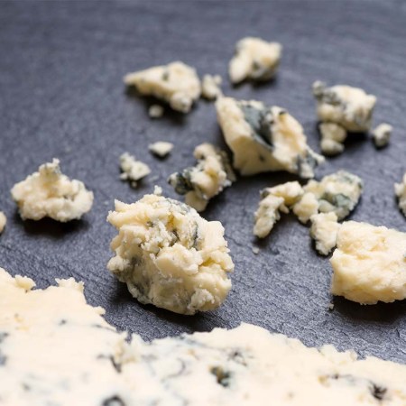 top view of tasty pieces cheese with blue mold on black slate background. An Oregon brewery just made a beer out of blue cheese.