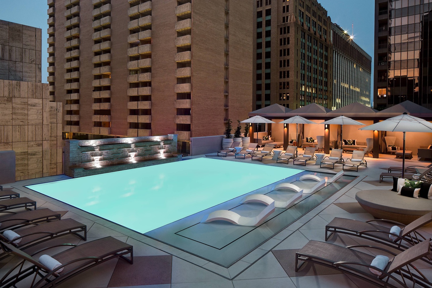 Pool on rooftop with chairs and tables with umbrellas 