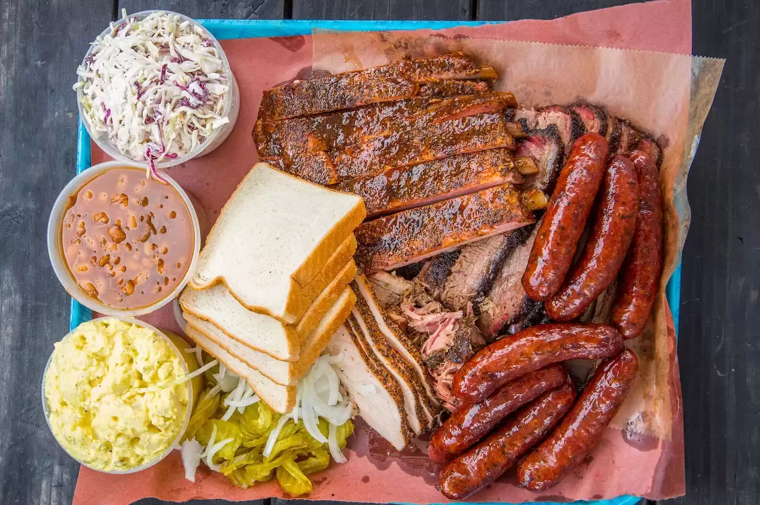 Meat, bread, coleslaw, beans and potato salad on a tray
