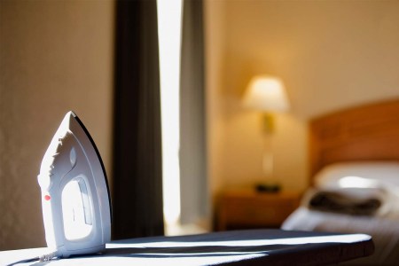 A hotel iron sitting on an ironing board. Here's why you should never use the iron in your hotel on your clothes.