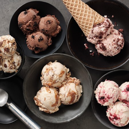 Scoops of ice cream in a bowl with a cone and an ice cream scoop from a birds-eye view
