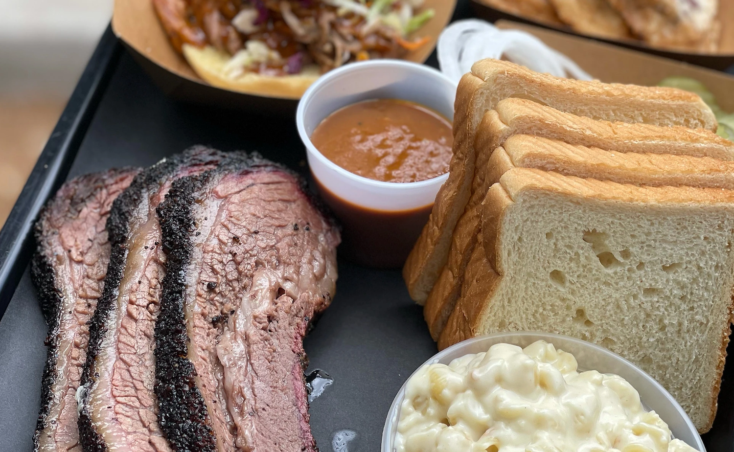 Close-up of meat, bread, sauce and mac and cheese on a tray
