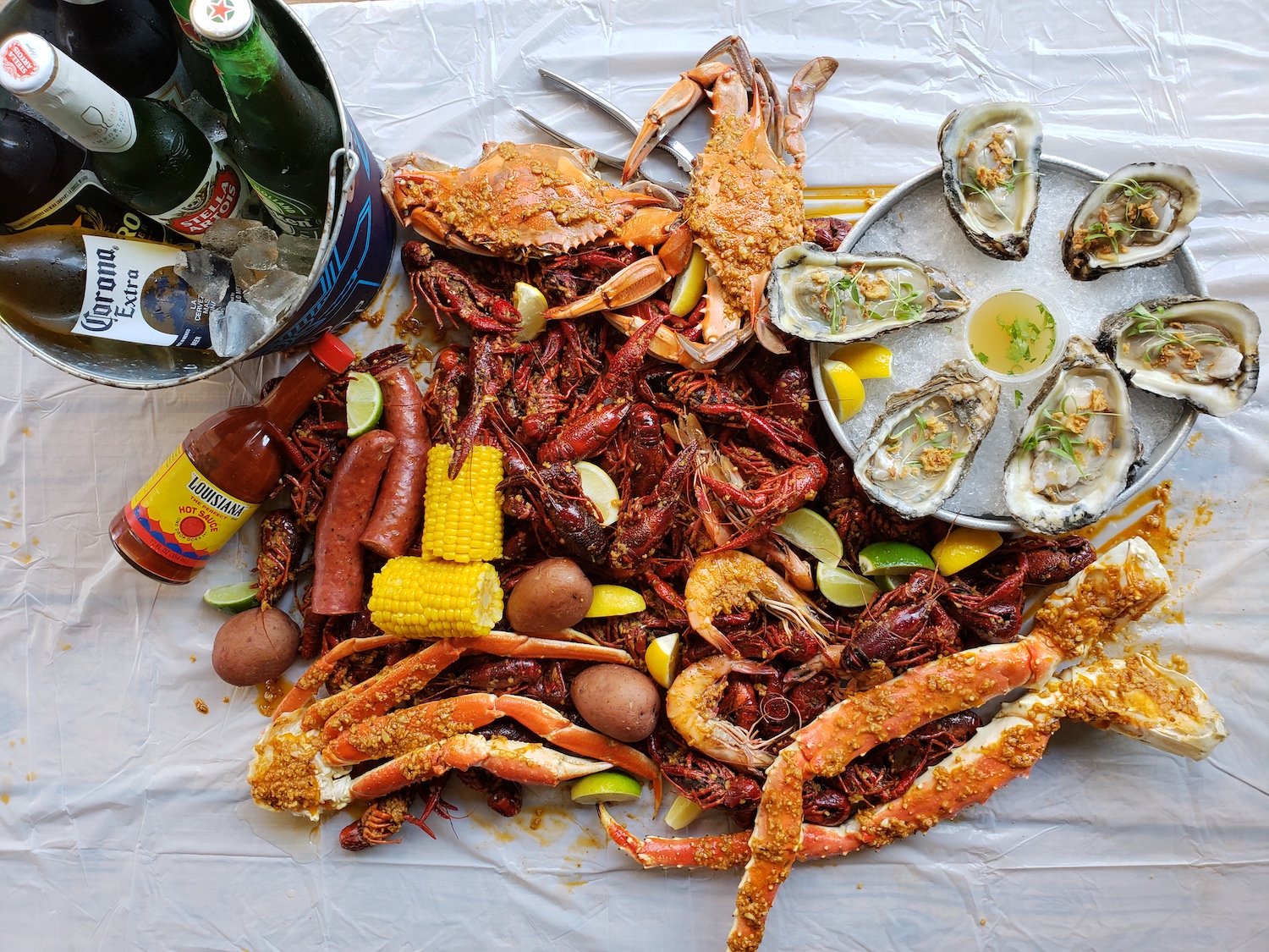 Crawfish, shrimp, crab, oysters, potatoes, corn and beer in a pile
