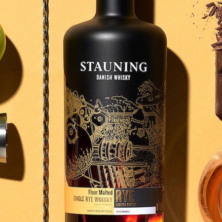 Stauning, a Danish rye whiskey, on a table with whisky, chocolate, a jigger and an apple. Stauning is one of several whisky brands around the globe offering rye.
