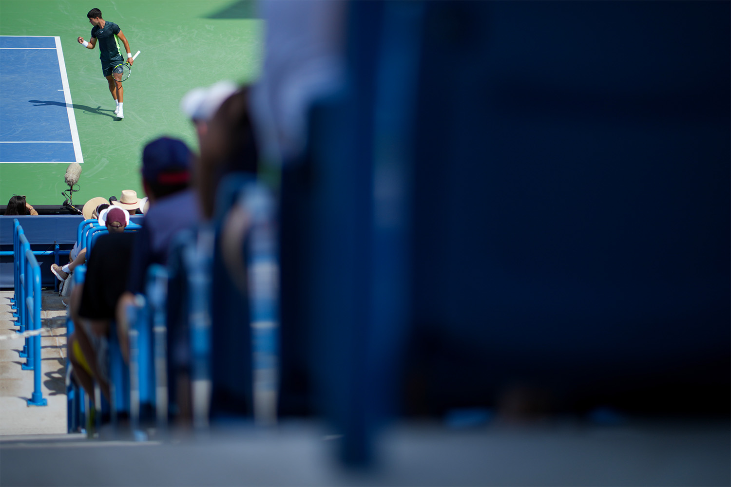 A view of Carlos Alcaraz from the aisles of a small tennis arena in Australia.
