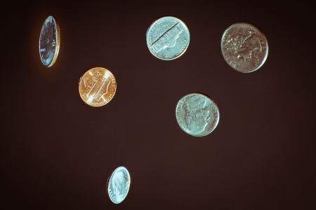 Various U.S. coins in the air on a dark background. New research suggests flipping a coin comes with a slightly favorable bias to one side.