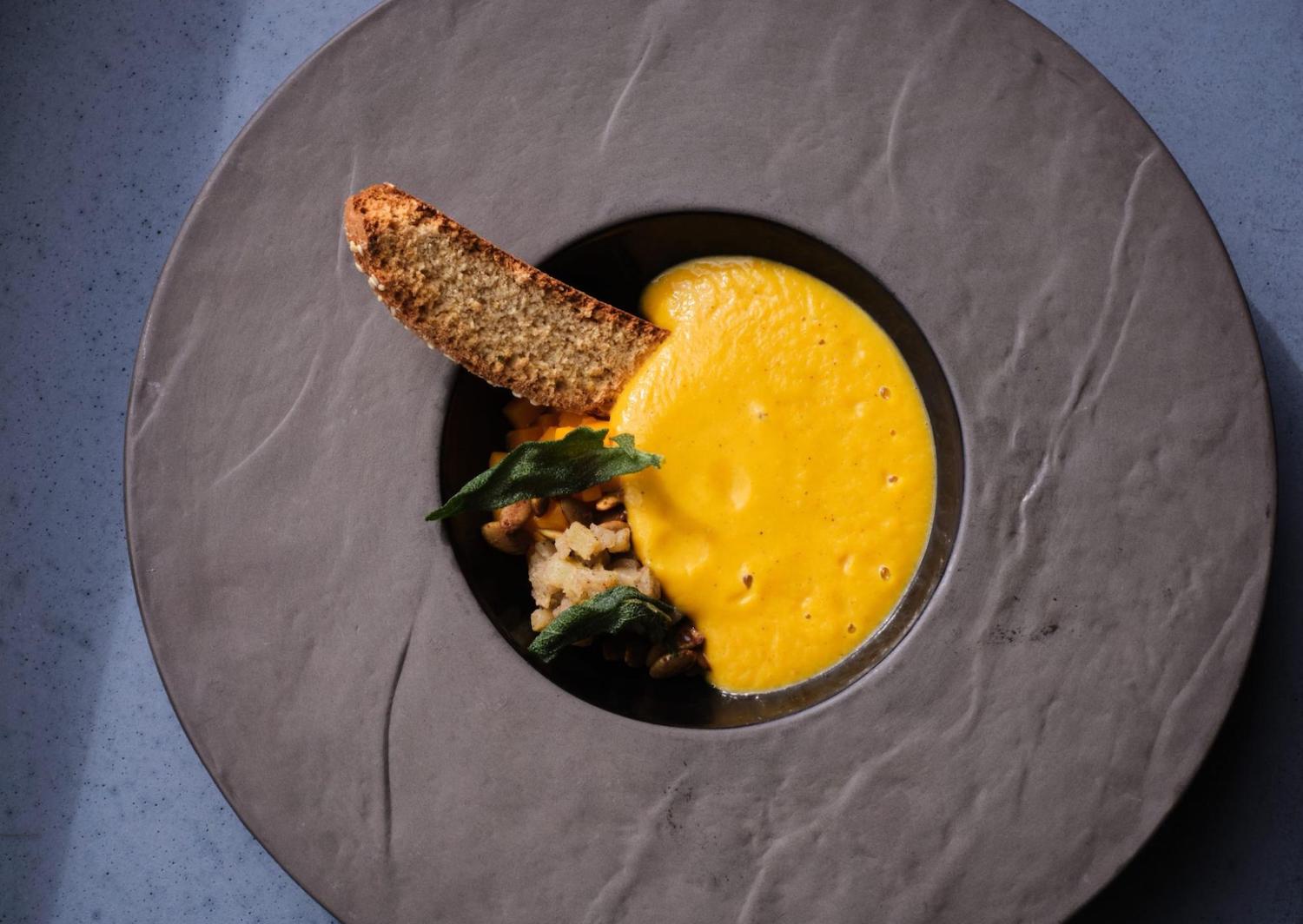 Slice of bread dipped in sauce in a bowl-like piece of kitchenware