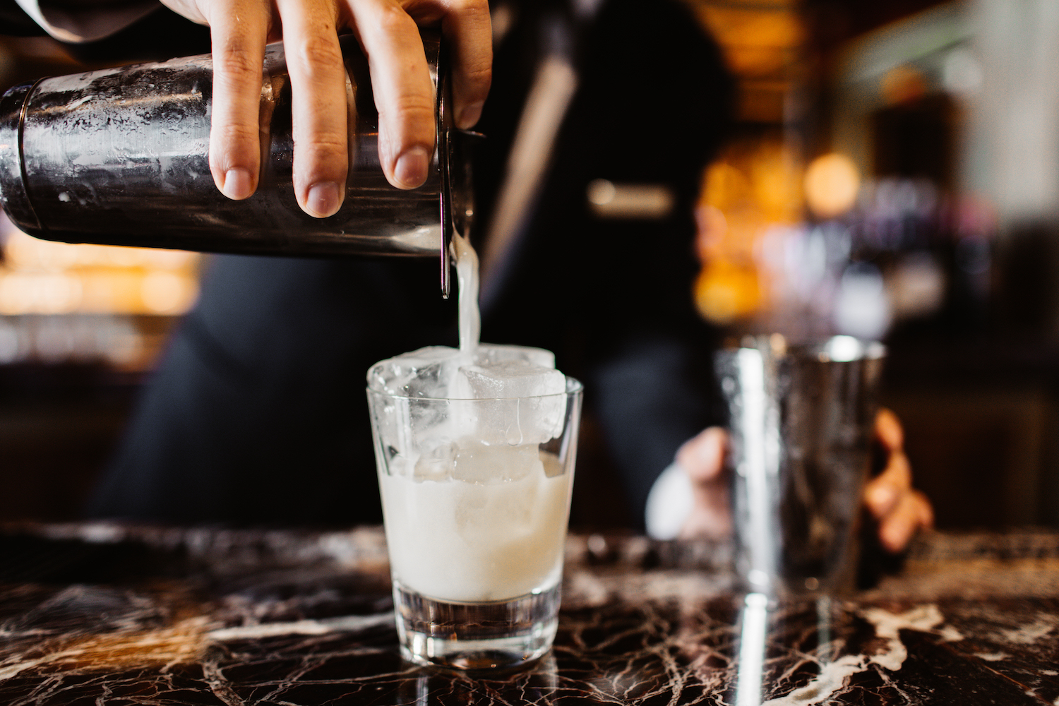 Drink being strained through a shaker on a bar counter