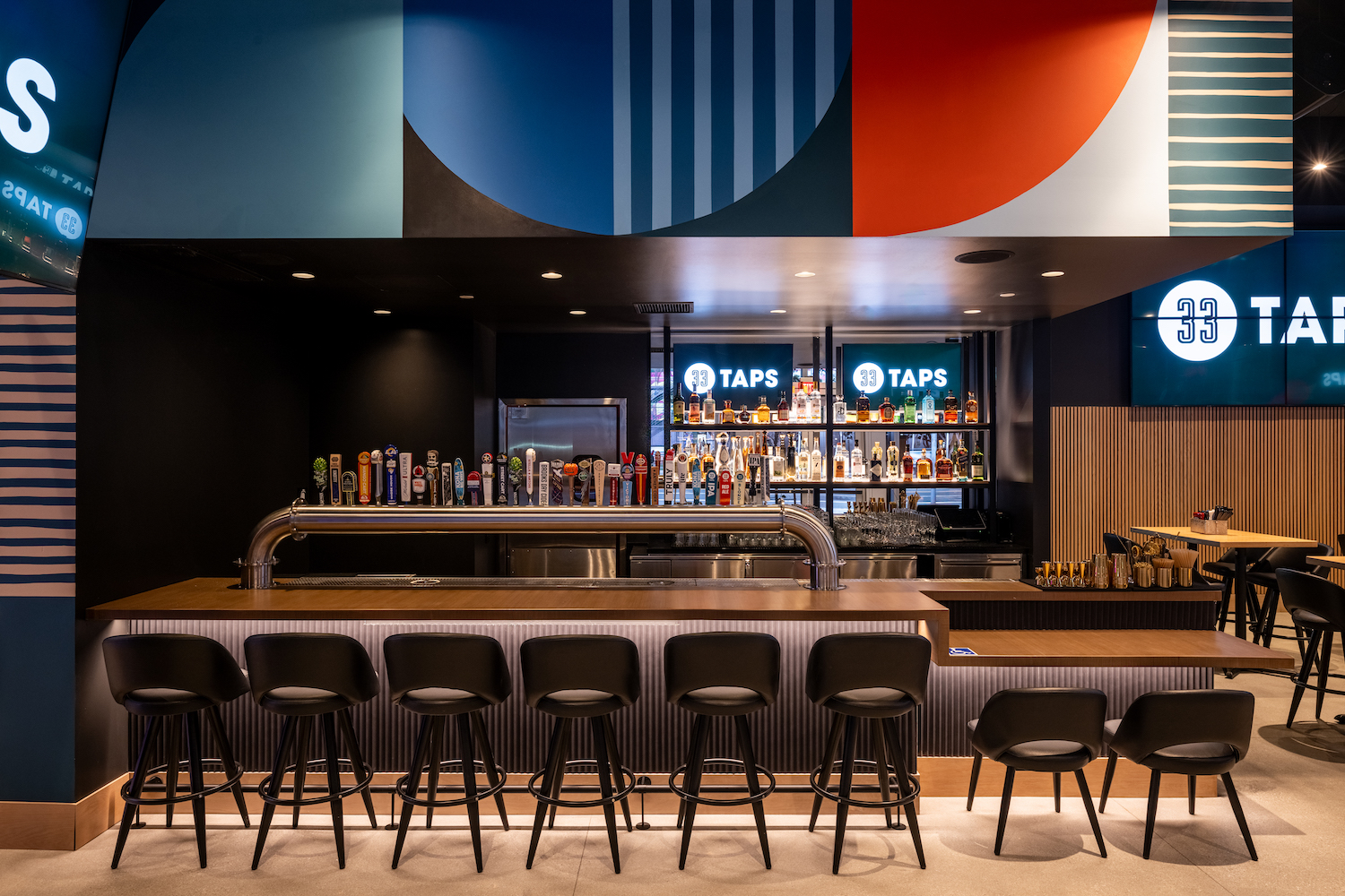 Bar area with a focus on the large row of beer taps in the center of the bar