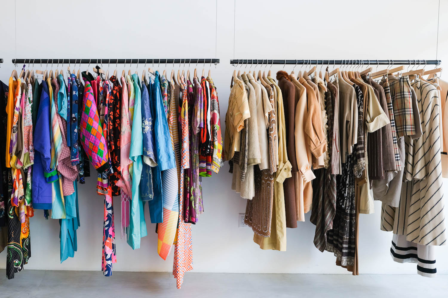 Various colored clothing hanging from hangers on a rack in a store