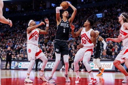 Victor Wembanyama (Wemby) of the San Antonio Spurs looks to the basket as he's defended by Bruce Brown #11 and Ochai Agbaji #30 of the Toronto Raptors in an NBA game on February 12, 2024
