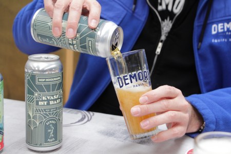 a hand pouring kvass ist das into a pint glass