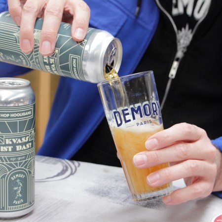 a hand pouring kvass ist das into a pint glass