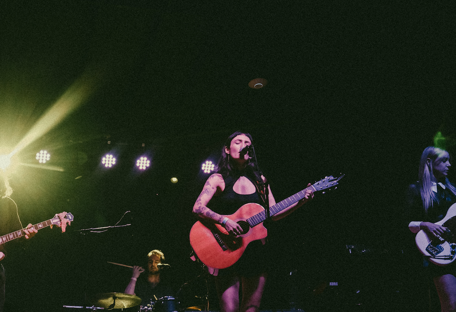 Woman with a guitar singing into a microphone on a stage
