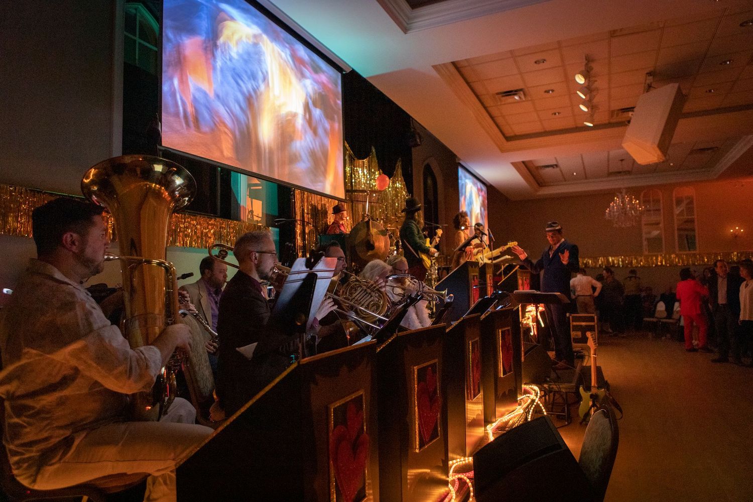 People lined up on a stage in front of a TV playing instruments