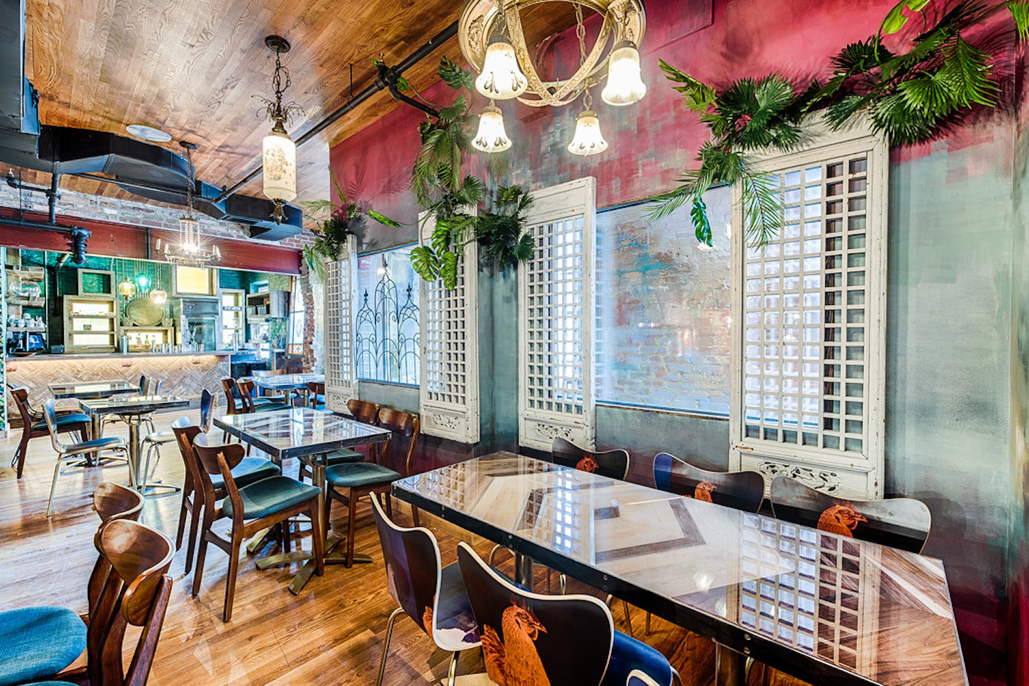 Seating area with tables. chairs, chandeliers and greenery