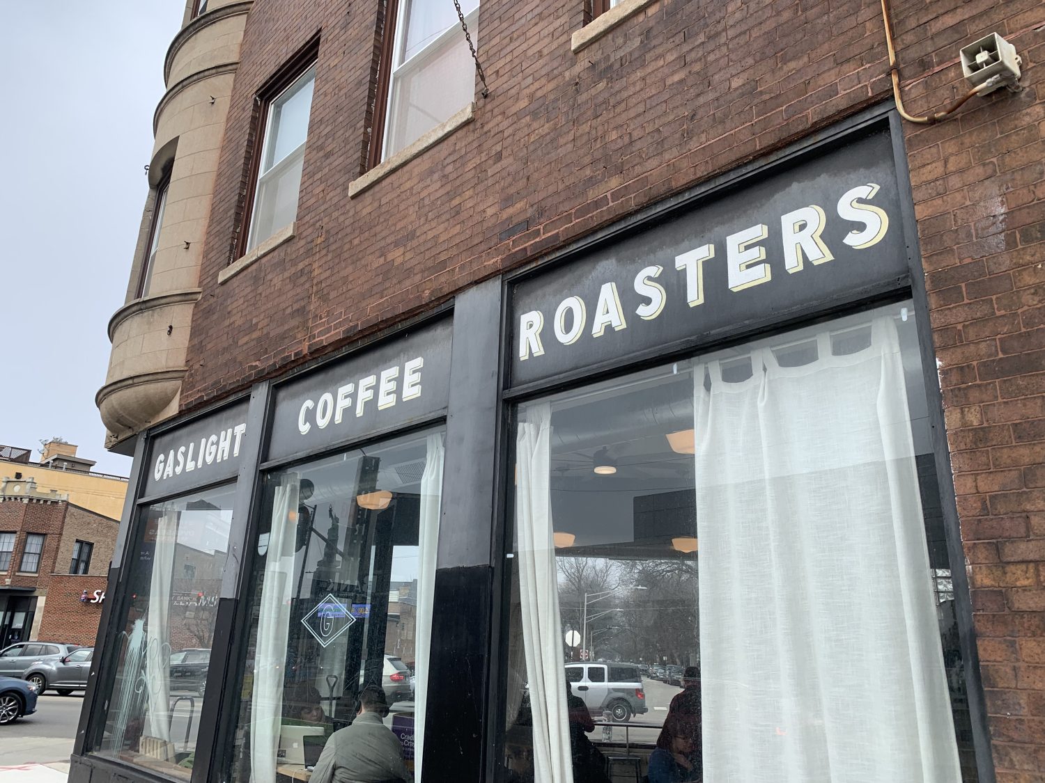 brick building with coffee sign, big windows with white curtains