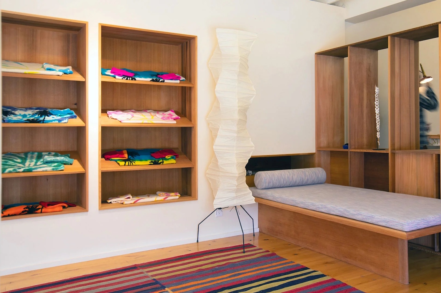 Interior of The Elder Statesman, with shirts folded on shelves next to a large gray elevated mat with a pillow