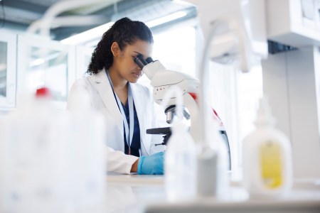 Scientist in lab looking into a microscope