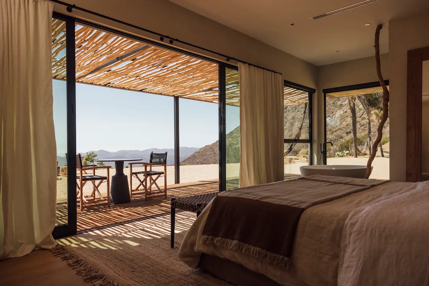inside of house with bed and open sliding door, view of mountains, chairs
