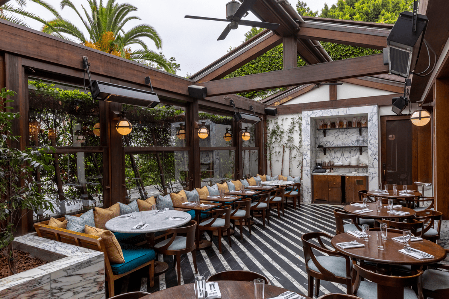 outside tables with couches, yellow pillows, lanterns, striped floor