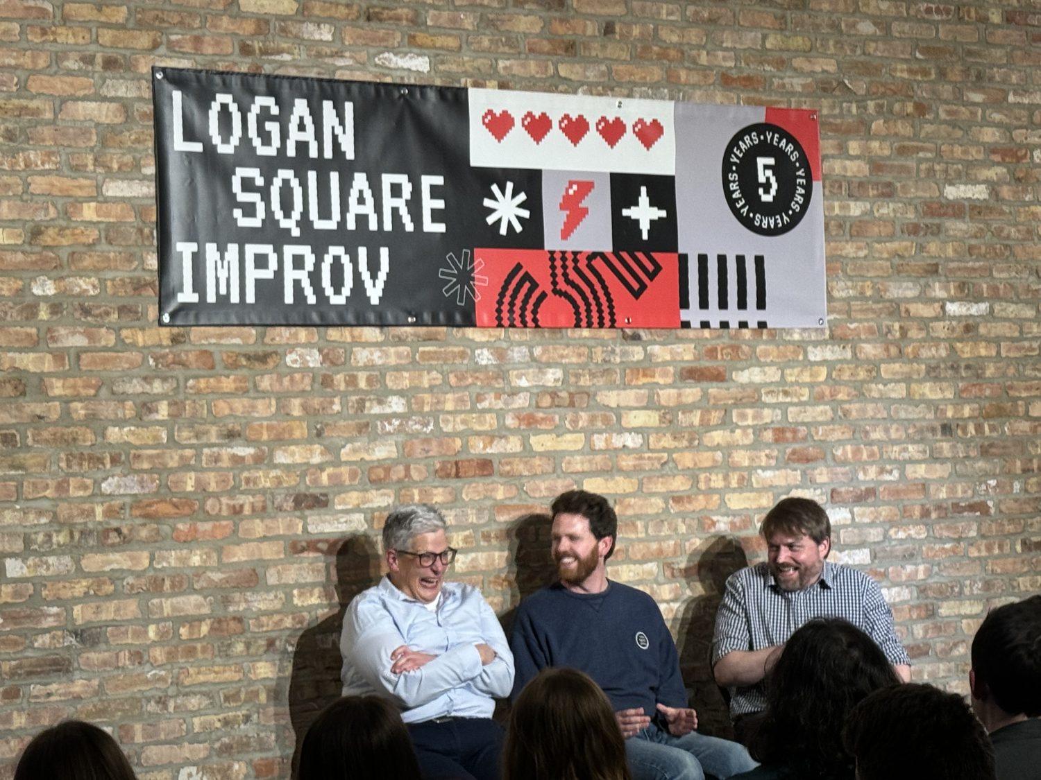 people sitting below a sign with brick wall