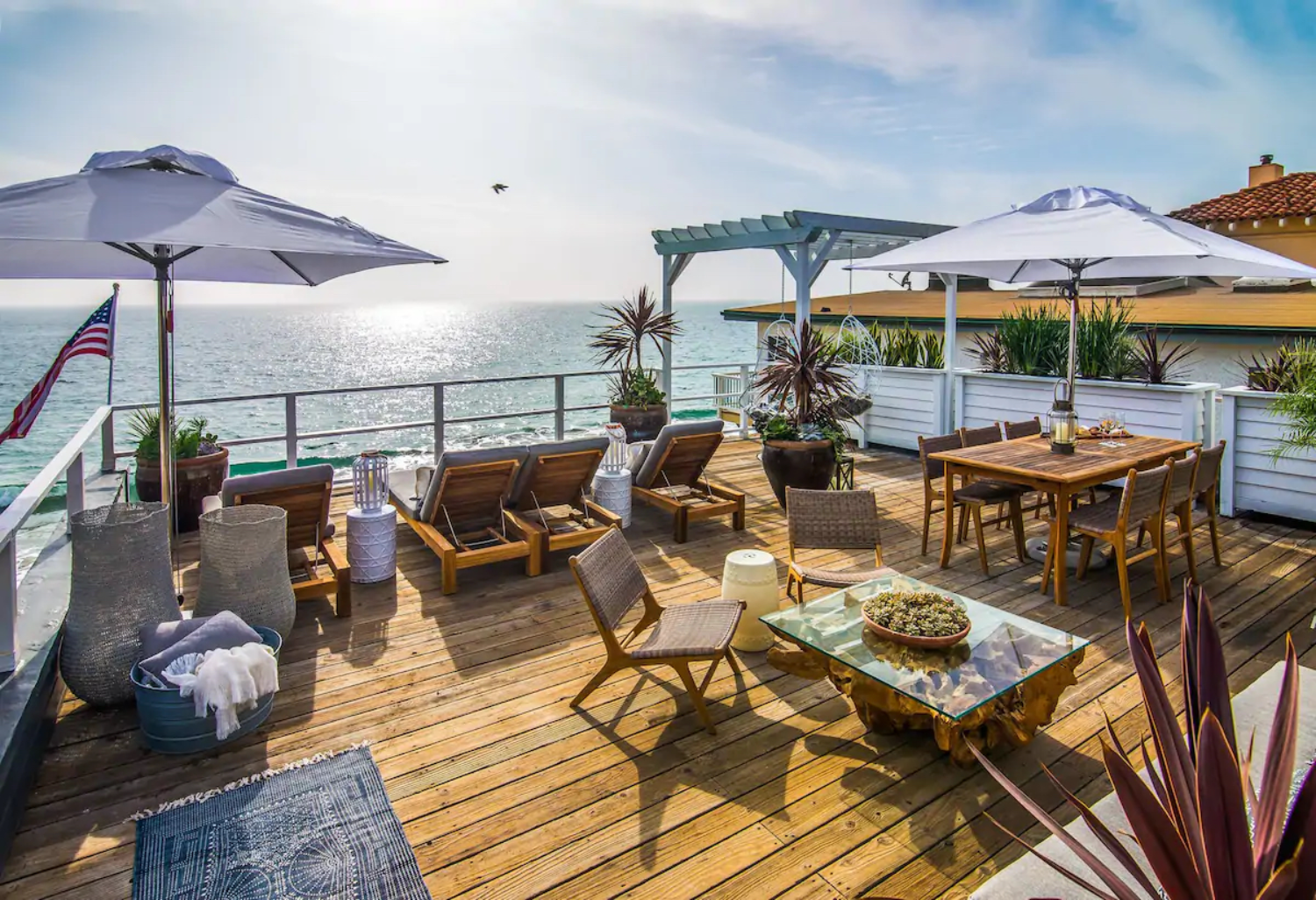 deck with plants, umbrellas, chairs, tables overlooking water