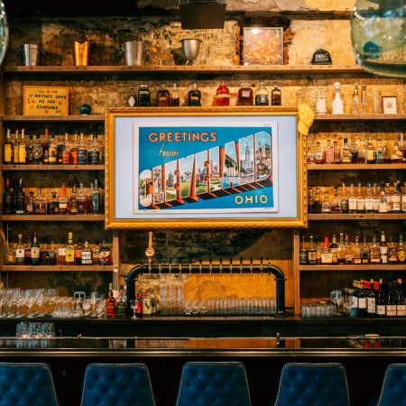 a bar with a sign hanging over the bottles that reads welcome to cleveland