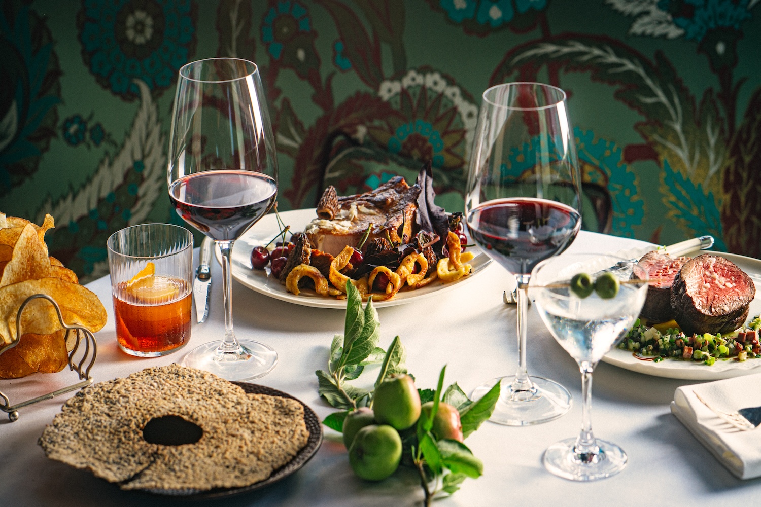 plates of food, two wine glasses, green wallpaper
