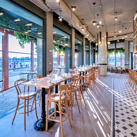 a light filled wine bar with a black and white tiled floor and wall of windows