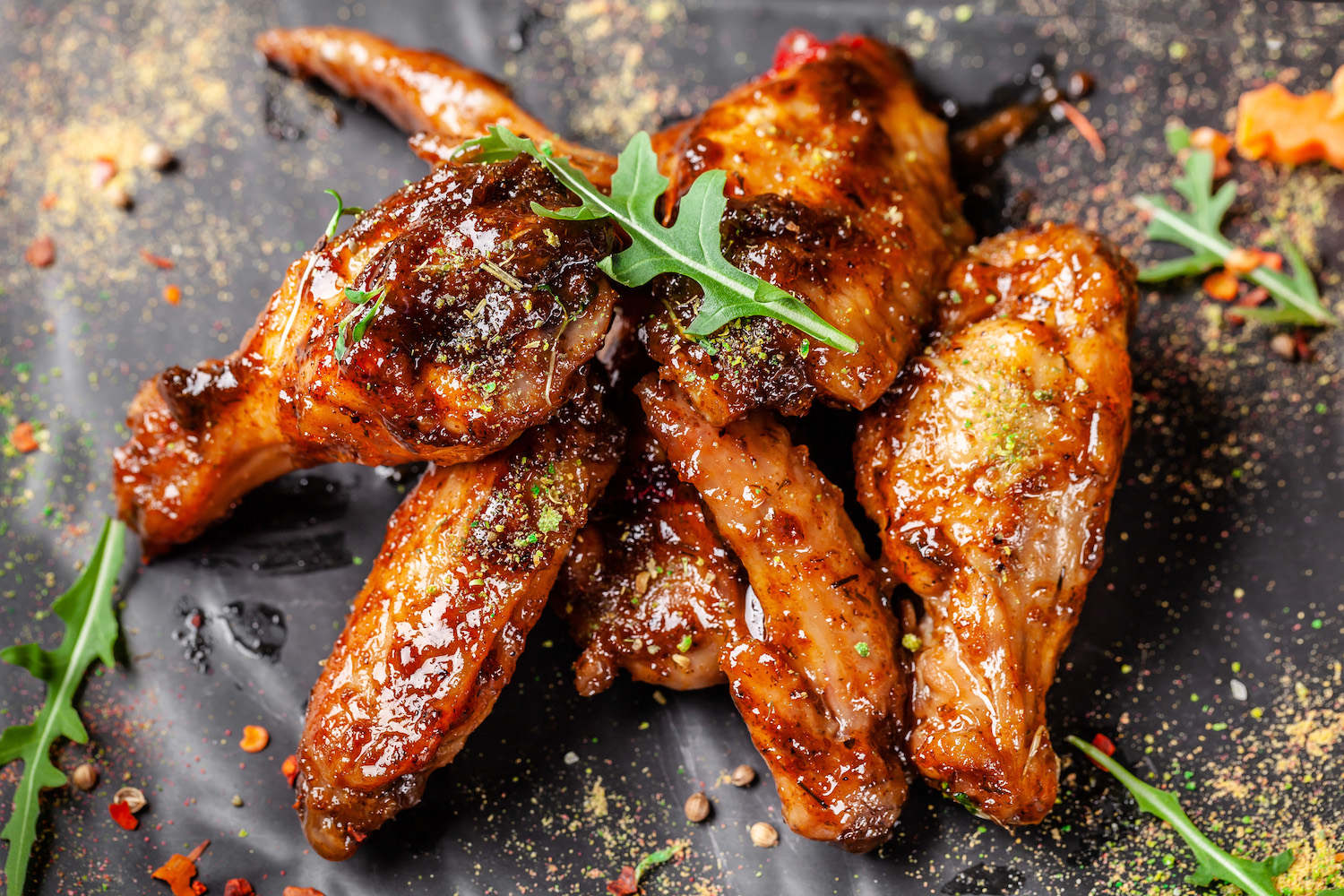 Baked chicken wings and legs in honey mustard sauce. Serving dishes in the restaurant on a black plate