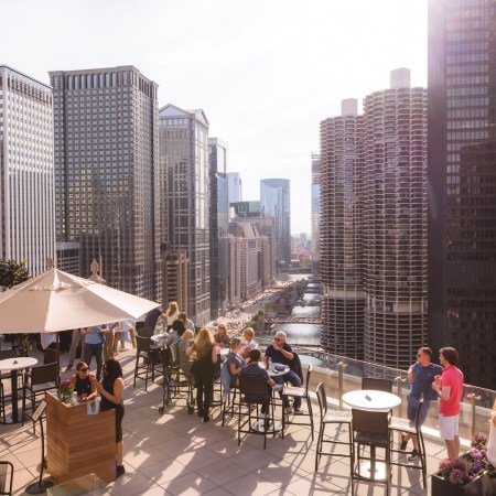 people on rooftop on sunny day, umbrella, chairs and tables, buildings