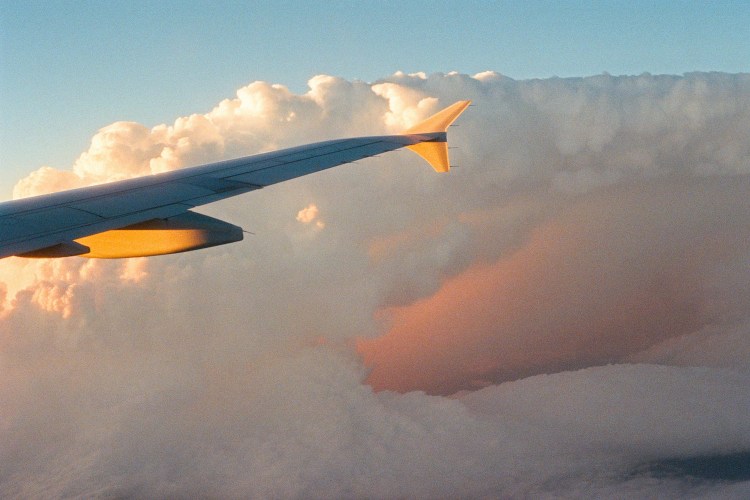 A plane wing passing through clouds.