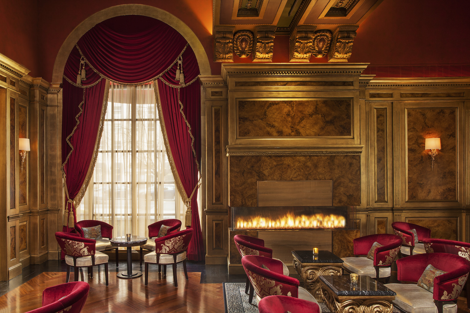 room with red curtains, red chairs, fireplace