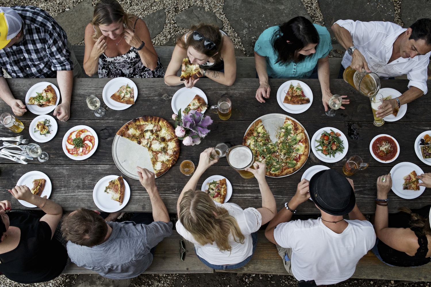 angle from above, people sitting at a booth eating pizza
