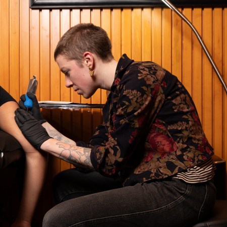 A person gives someone a tattoo on their arm.