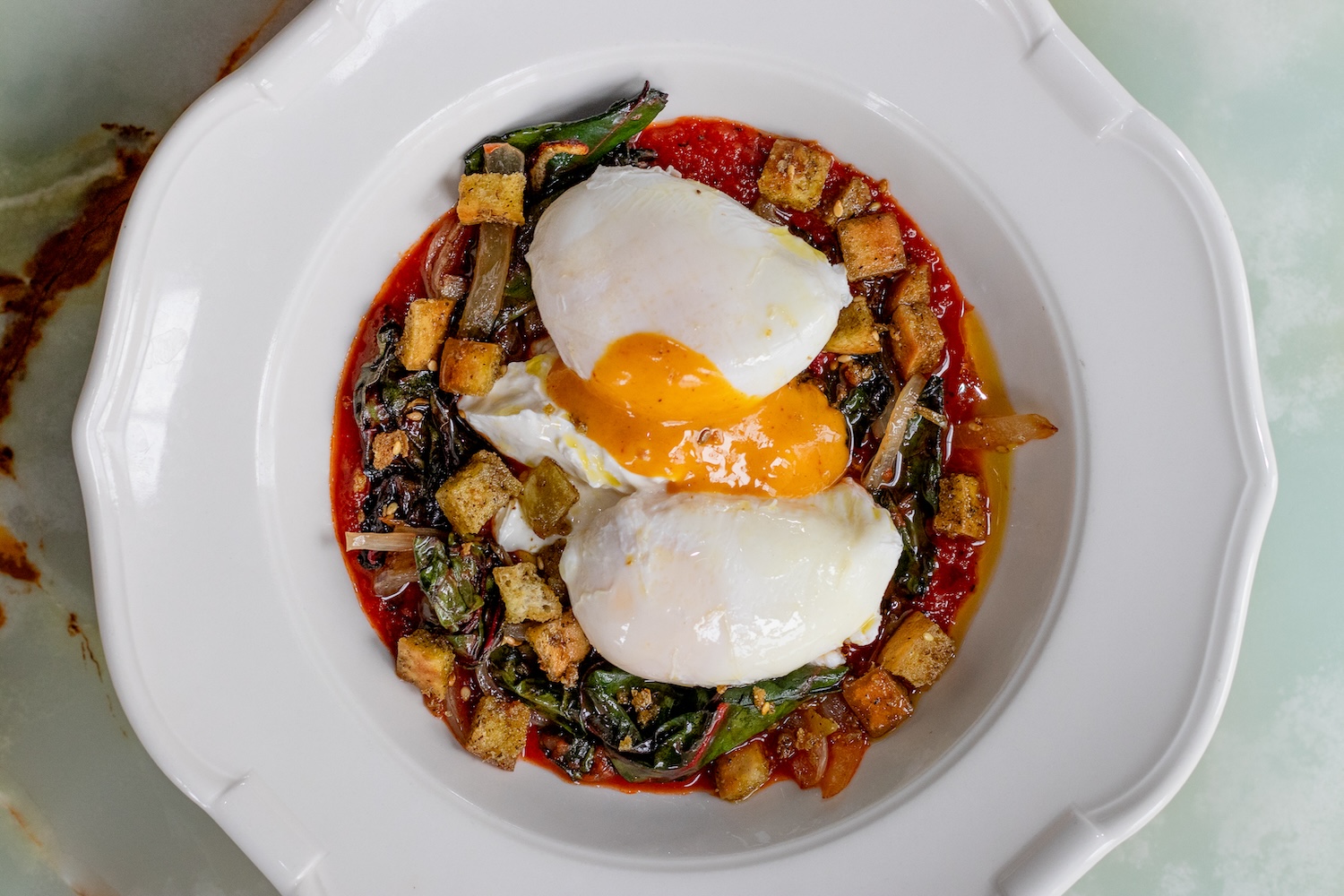 eggs, croutons, and vegetables in a red sauce
