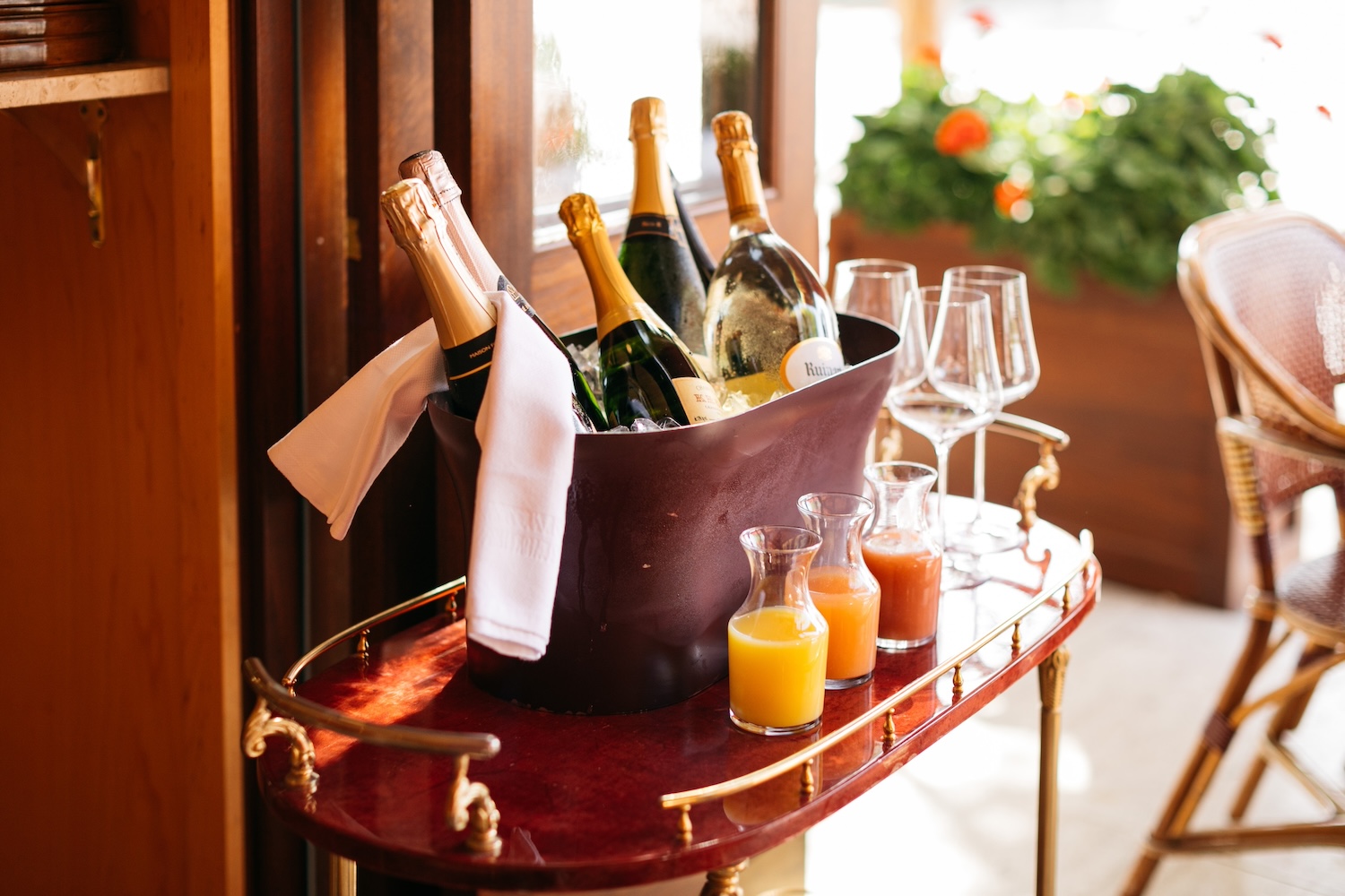 bottles of champagne, napkin, bottles of orange juice, glasses, on a cart